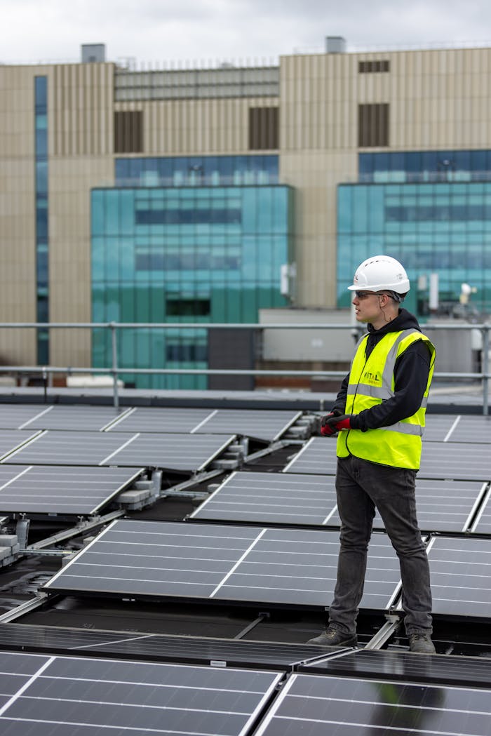 A worker in a safety vest and helmet inspects solar panels on an urban rooftop, promoting renewable energy.